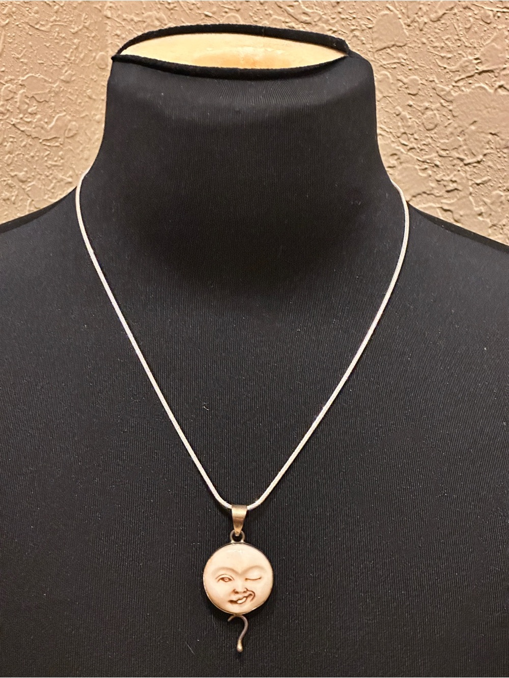 Celestial-style pendant necklace featuring a round, carved winking moon face